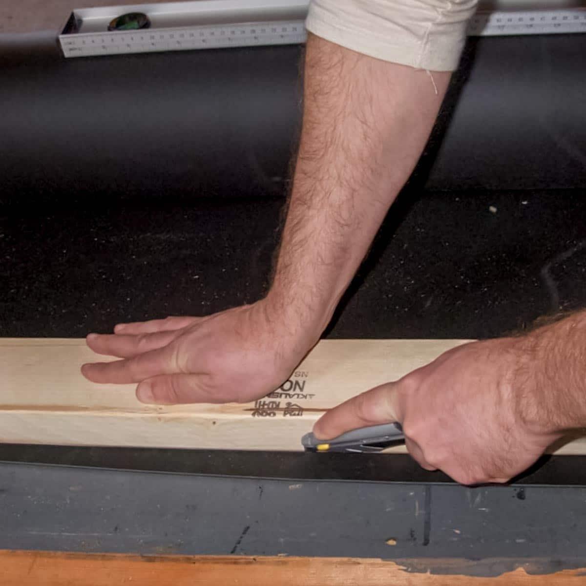 Soundproofing a Garage — Use a straight edge and utility knife to cut the barrier to the size you need.