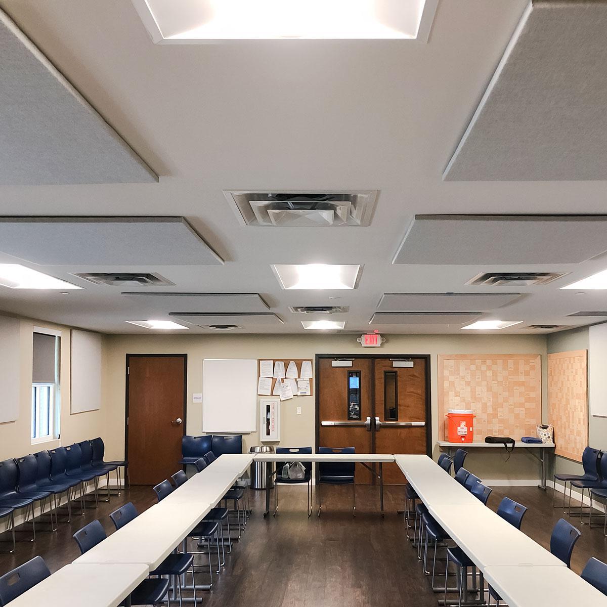 Fabric wrapped acoustic panels on the ceiling improve the acoustics in the Dallas 24 Hour meeting space.