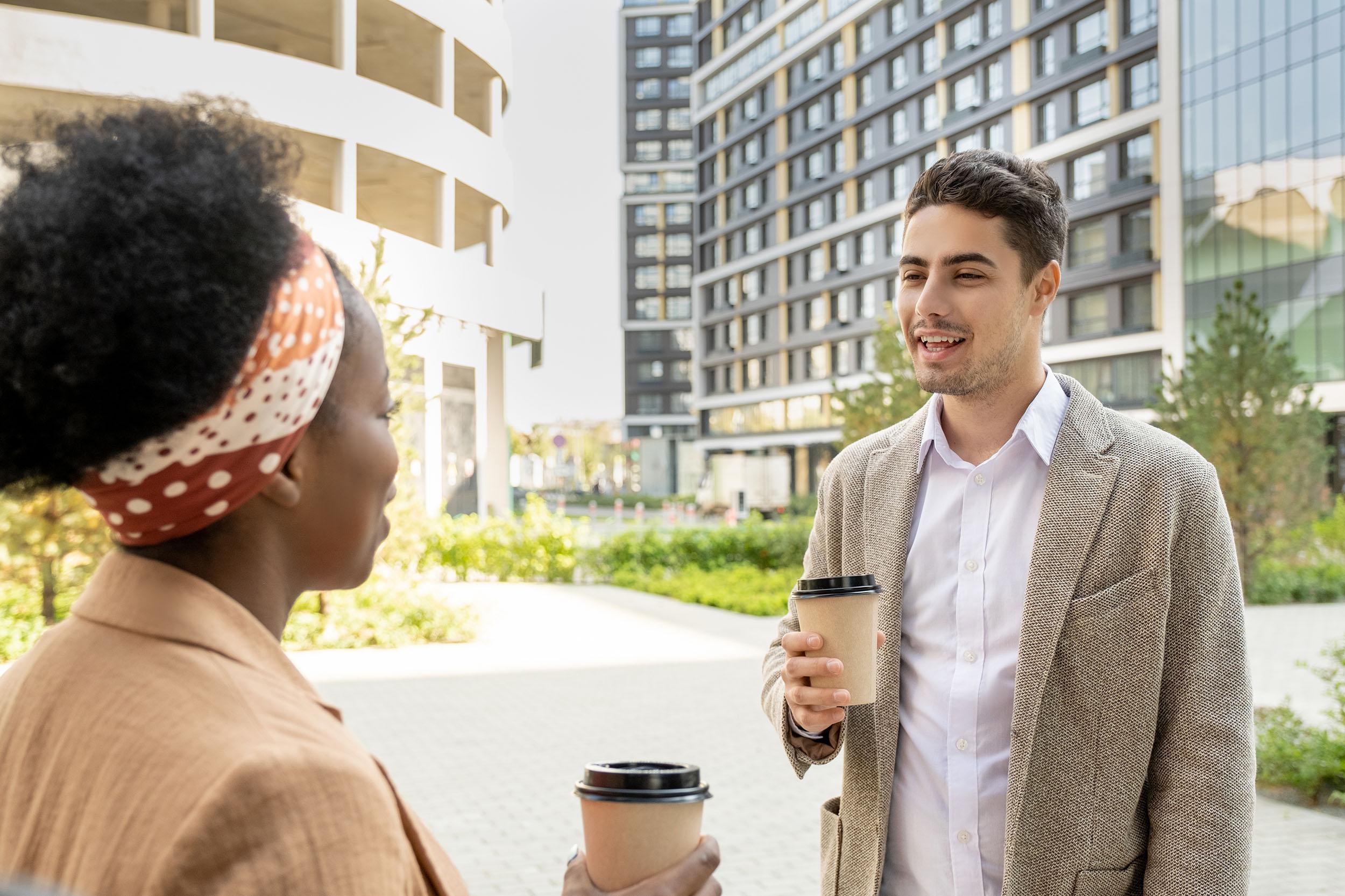 Two businesspeople talk outdoors over coffee. Photo by shironosov on iStock.