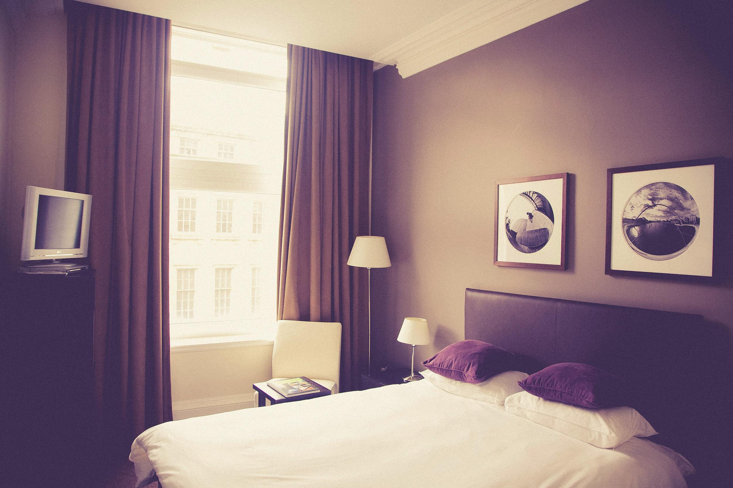 Hotel Room with bed and curtained window Photo by Markus Spiske on Unsplash