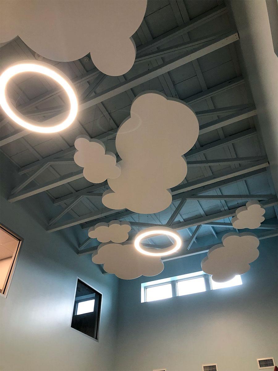 Custom cut foam acoustic clouds on the ceiling of a daycare reduce sound in the space.