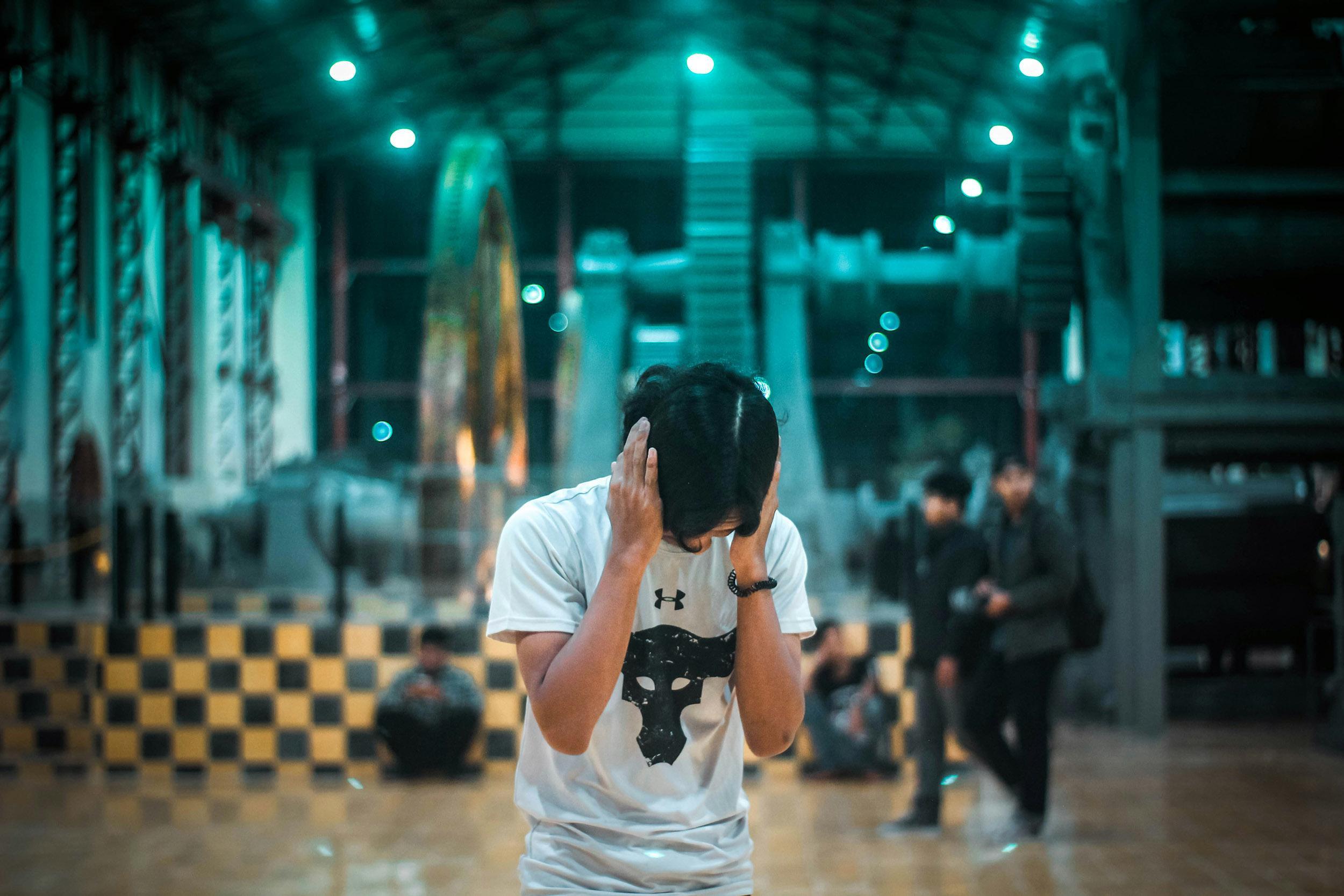 Man holding hands over ears from noise. Photo by chairulfajar on  Unsplash.