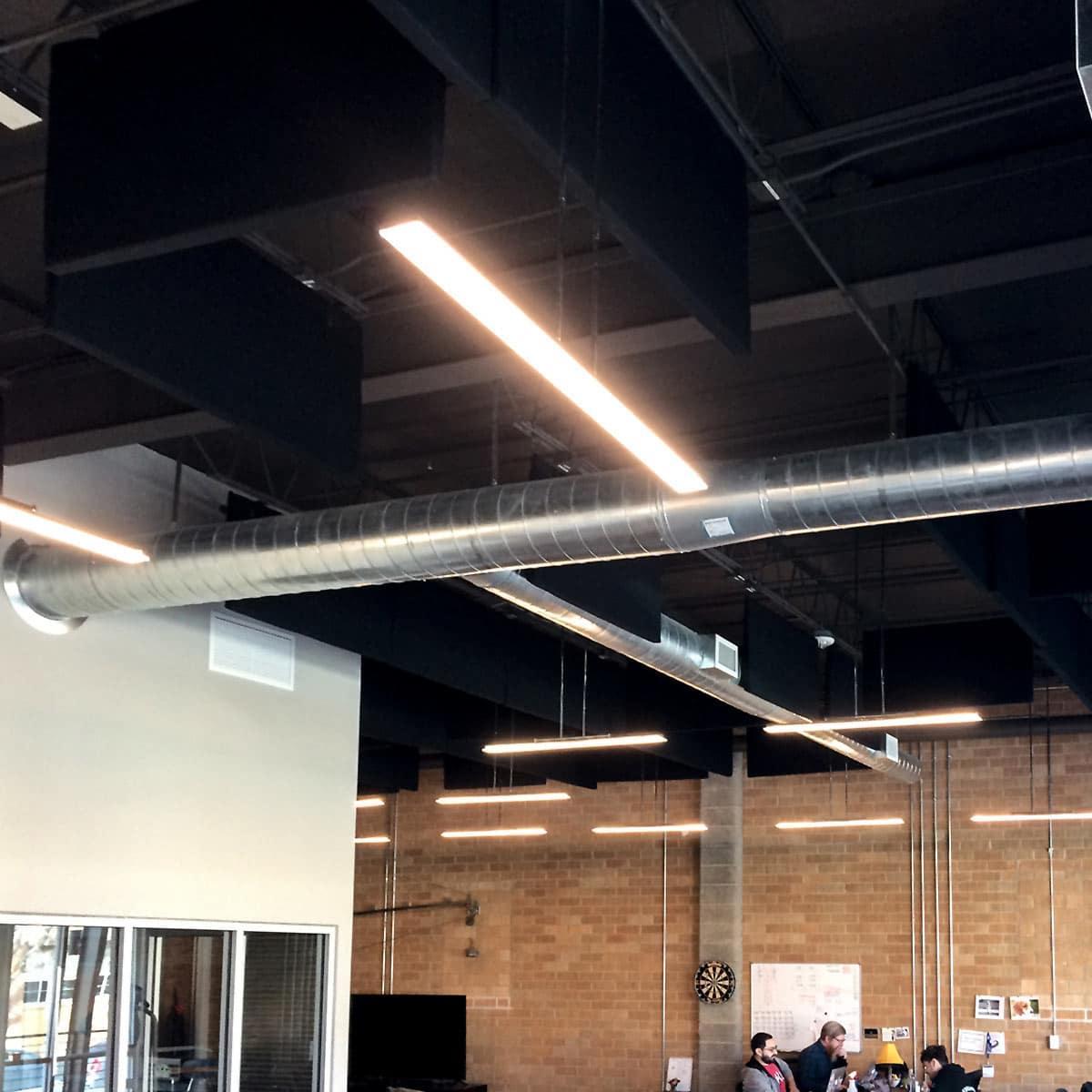 PremiumBeat Open Office Plan - The fabric wrapped acoustical baffles installed in the ceiling help to lower the reverberation time to increase speech intelligibility.