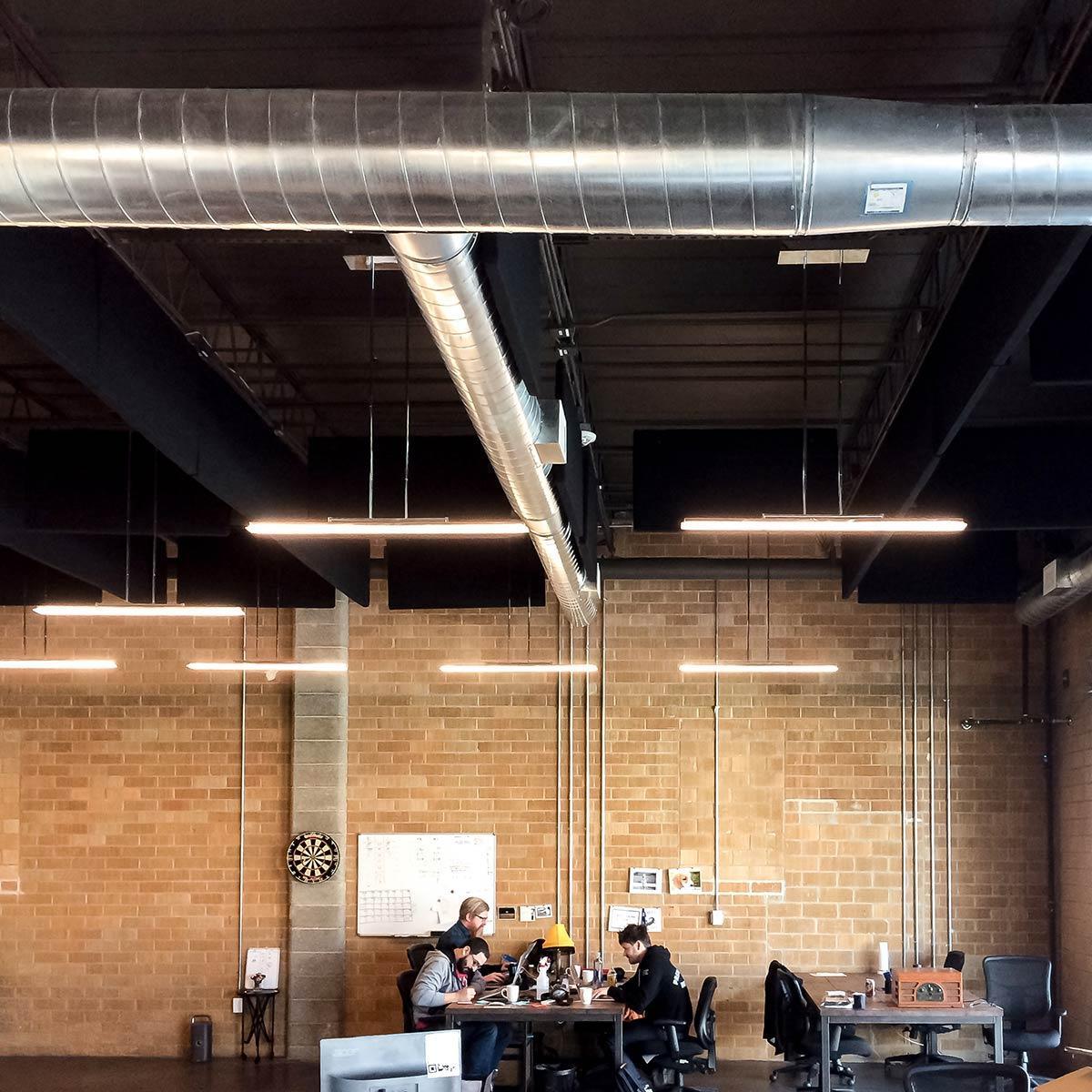 PremiumBeat Open Office Plan – The fabric wrapped acoustical baffles installed in the ceiling help to lower the reverberation time to increase speech intelligibility.