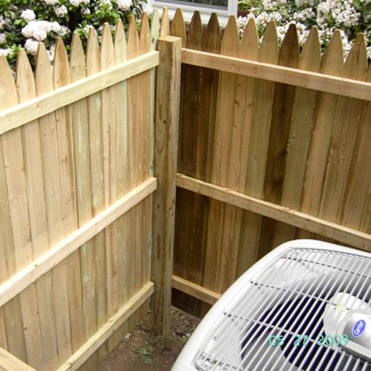 Residential HVAC with fence built around it and no acoustic treatment.