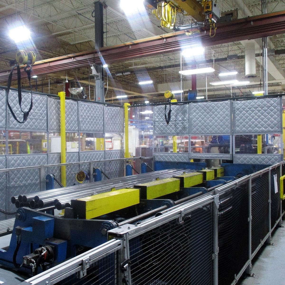 PrivacyShield® Dual-Sided Absorptive Soundproofing Blankets surround a TCO workcell to comply with OSHA standards.